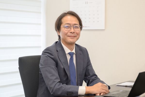 机に座って微笑む社長